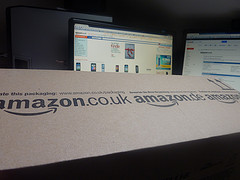 Foto eines Amazonpakets vor einem Monitor mit Amazonwebseite